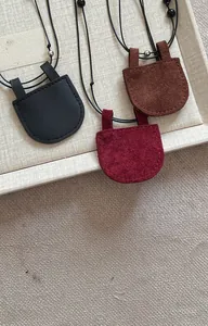 Detailopname van drie suède ronde hangerkettingen in zwart, bruin en rood