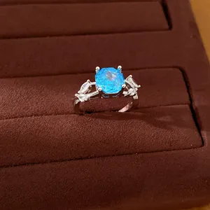 Close-up detail of elegant silver ring with sky blue square zircon and clear side stones