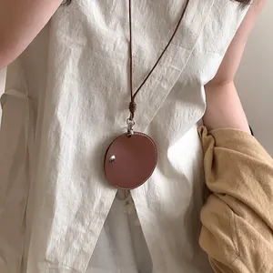 Detail van minimalistische ronde leren hanger ketting die dient als hippe brillenhouder.