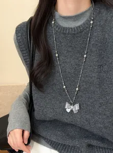 Ketting met polkadot strik hanger gedragen op een grijze gebreide trui voor mode.