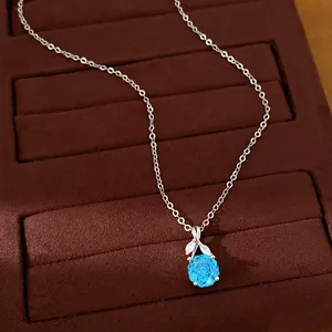 Close-up of elegant blue zircon flower pendant with silver chain on brown velvet tray