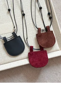 Detailopname van ronde kunstlederen brillenhouder hangers in zwart, rood en bruin