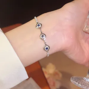 Detailaufnahme eines funkelnden Zirkon-Armbands mit blauem Auge und silbernem Finish