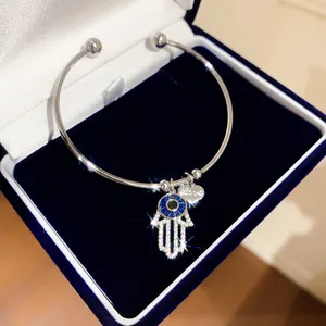Detailansicht eines Hamsa-Hand-Armbands mit blauem Auge und Zirkonia in einer Box.