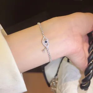 Detailaufnahme eines silbernen Armbands mit funkelndem bösen Blick und blauem Zirkon