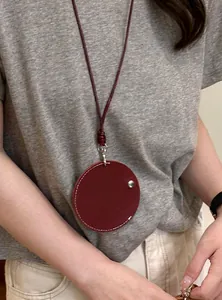 Detail van een bordeauxrode lederen ronde hanger ketting als brilhouder op een model