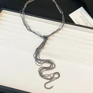 Vue détaillée d'un collier à pompon en chaîne multicouche noué argent foncé sur plateau