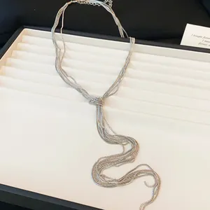 Vue détaillée d'un collier à chaînes multiples argenté avec un nœud et des pompons élégants