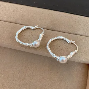 Macro detail of French vintage textured silver hoop earrings with elegant round pearls