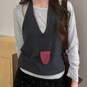 Close-up detail of a burgundy magnetic glasses holder necklace styled with a grey vest
