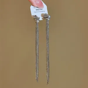 Vue détaillée de boucles d'oreilles argentées minimalistes avec nœuds et longs pompons