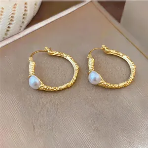 Macro detail of French vintage gold textured hoop earrings with elegant pearl accents