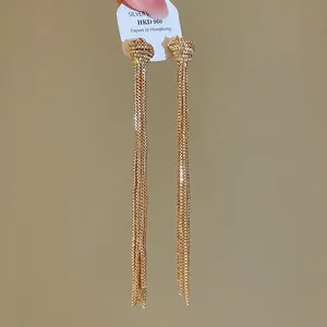 Gros plan sur d'élégantes boucles d'oreilles dorées avec nœuds et longues franges en chaîne