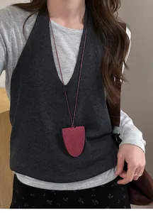 Detail shot of a minimalist burgundy suede magnetic glasses clip necklace on grey knitwear