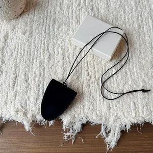 Minimalist black leather bell pendant necklace for glasses on textured background