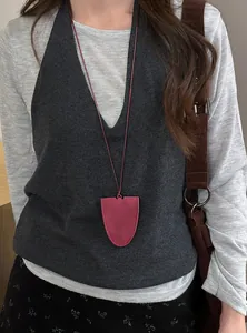 Close-up detail of a minimalist burgundy leather magnetic pouch necklace and glasses clip