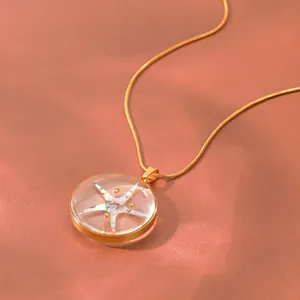 Detailaufnahme einer goldenen Halskette mit einem Anhänger aus klarem Seesternharz