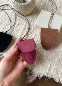 Close-up of a burgundy magnetic leather eyeglass holder necklace pendant with stitching.