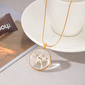 Detailansicht einer goldenen Kette mit transparentem Harz-Seestern-Anhänger auf Tasse.