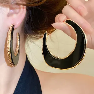 Detaillierte Nahaufnahme eleganter schwarz-goldener mondförmiger C-Ohrringe für Damen