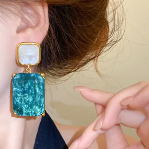Detailansicht eleganter blauer quadratischer Harzohrringe, die von einem Modell getragen werden