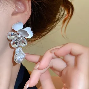 Luxe zilveren bloem oorbellen met sprankelende kristallen en barokke parel op model