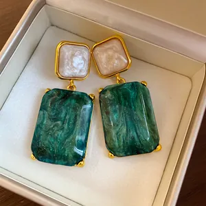 Detailansicht eleganter grüner quadratischer Harzohrringe mit Marmormuster in einer Schmuckschachtel
