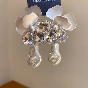 Macro detail of elegant flower petal earrings with cluster crystals and baroque pearls