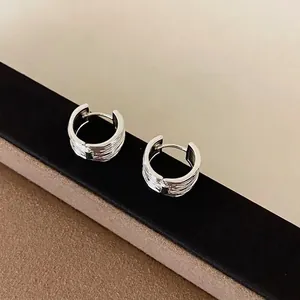 Detailweergave van zilveren creolen met textuur en een Frans minimalistisch design