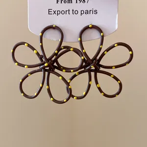 Close-up of brown floral hollow earrings with yellow polka dots on display card