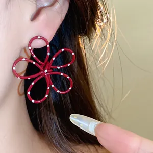 Detail view of red metal flower stud earring with white polka dots worn on ear