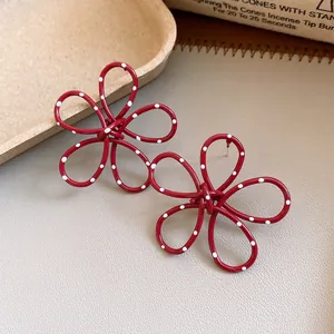 Close-up of red hollow flower earrings with white polka dots and hypoallergenic silver needle