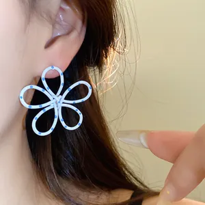 Macro view of white metal flower ear stud featuring blue polka dots and hollow design