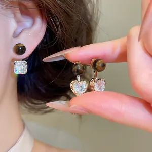 Detail of Maillard style earrings with tiger eye beads and heart-shaped zircon pendants.