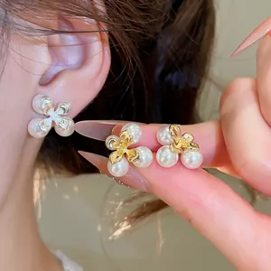 Primo piano di eleganti orecchini a lobo con perle a forma di fiore e perno in argento