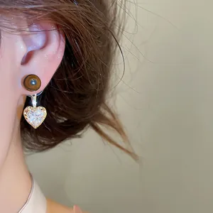 Detailed close-up view of elegant brown heart-shaped zircon drop earrings worn on ear