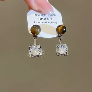 Close-up of Maillard style stud earrings featuring tiger's eye and shiny zircon