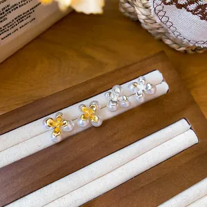 Primo piano di eleganti orecchini a lobo a fiore con perle in oro e argento sul display