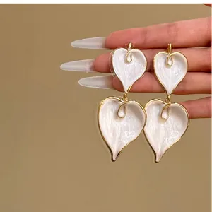Detailed view of retro white enamel heart earrings featuring elegant gold-plated edges