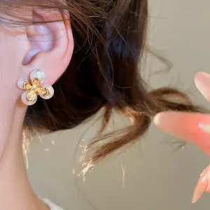Primo piano di un elegante orecchino a fiore con perle indossato sull'orecchio rosa