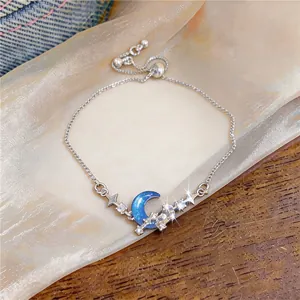 Detailed view of sparkling zircon crescent moon and star charms on adjustable silver bracelet