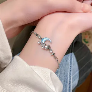 Detailed shot of a silver moon and star charm bracelet with blue zircon on wrist