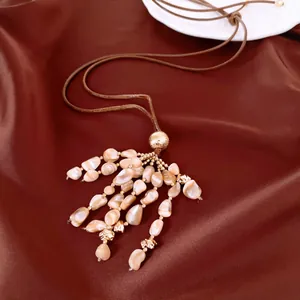 Gros plan du collier avec pendentif gland en coquillage et cordon en cuir marron sur soie
