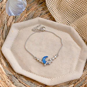 Close-up view of sparkling zircon moon and star bolero bracelet on a beige tray