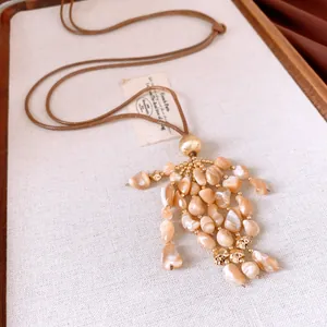 Vue détaillée d'un collier vintage avec pendentif à pampilles en nacre et cordon en cuir.