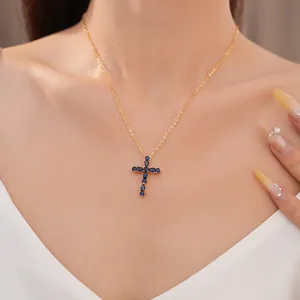 Vista detallada del collar de cruz chapado en oro con piedras azules en el cuello de una modelo
