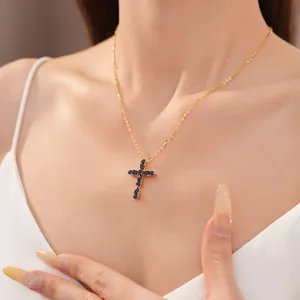 Detalle del collar de cruz de circón chapado en oro de 18k con piedras azules y cadena fina