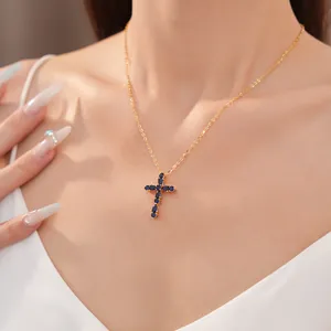 Primer plano de un collar de cruz chapado en oro de 18k con circonitas azul oscuro