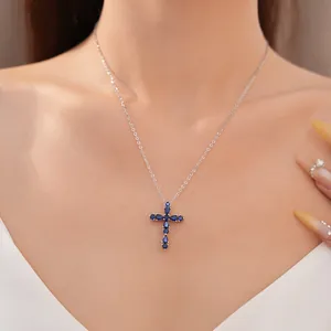 Elegante primer plano de un colgante de cruz de circón azul en cadena de plata.