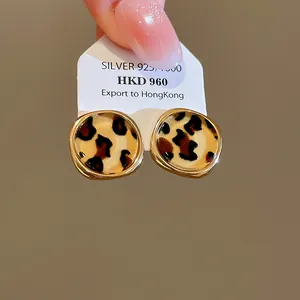 Nahaufnahme von Vintage-Leoparden-Ohrringen aus Acetat auf einer Displaykarte im Finger